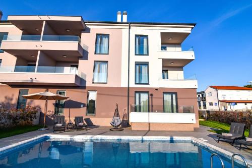 a building with a swimming pool in front of a building at Luxury apartment Porto with sea view and swimming pool in Premantura