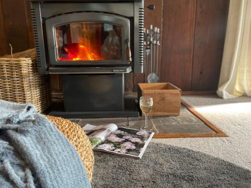 a fireplace with a glass of wine and a magazine at Browns Cottage in Bilpin