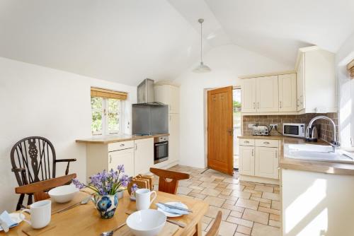 cocina con armarios blancos y mesa de madera en Little Pengelly Farm, en Crowan