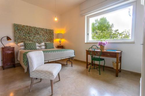 a bedroom with a bed and a desk and a window at Masseria Ferarelli Trepizzi in Diso