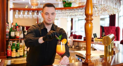 a man is making a drink at a bar at Victor's Residenz-Hotel Leipzig in Leipzig