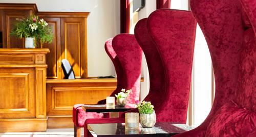 a room with red chairs and a table with flowers at Victor's Residenz-Hotel Leipzig in Leipzig