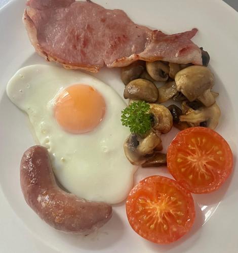 a breakfast plate with an egg bacon mushrooms and tomatoes at Little Pengelly Farm in Crowan