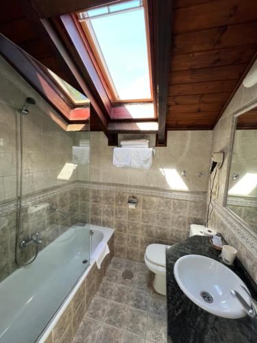 a bathroom with a tub and a toilet and a sink at Hotel Villa Maria in Revilla de Camargo