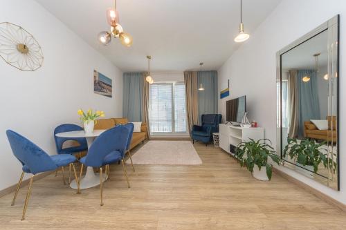 salon ze stołem i niebieskimi krzesłami w obiekcie Abrahama Comfort Apartments w mieście Gdynia