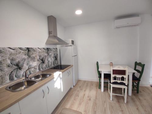 a kitchen with a sink and a table with chairs at Apartamento La Pedriza in Casabermeja