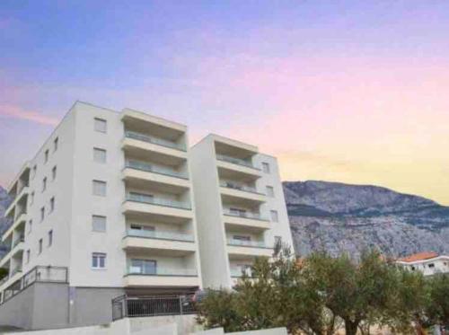 a white apartment building with a mountain in the background at Sunrise Makarska in Makarska