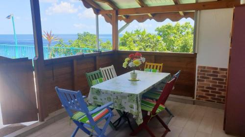 una mesa y sillas en un porche con vistas al océano en Bungalow d'une chambre avec vue sur la mer jardin clos et wifi a Deshaies, en Deshaies