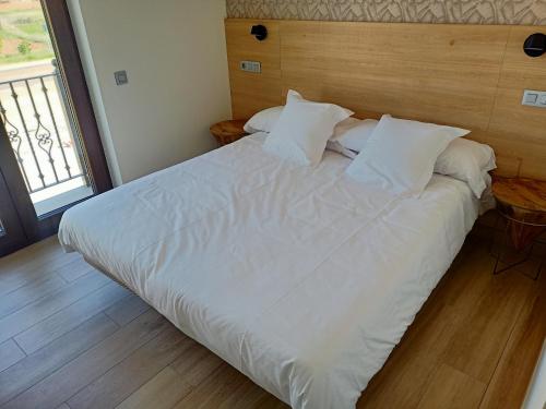 a large bed with white sheets and pillows in a bedroom at Albergue La Huella in San Martín del Camino