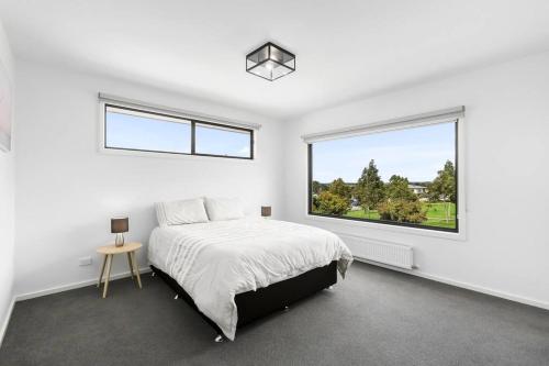 a white bedroom with a bed and a large window at Flagstaff Lodge in Portarlington