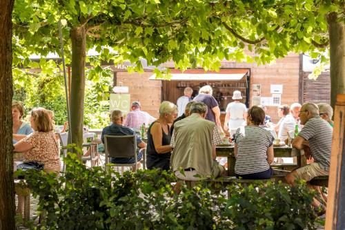 een groep mensen die aan tafel zitten in een tuin bij De Pastorie in Borgloon