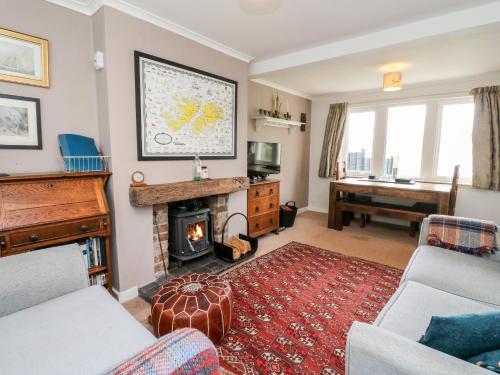 a living room with a fireplace and a piano at 12 Kenmore Cottages in Oban