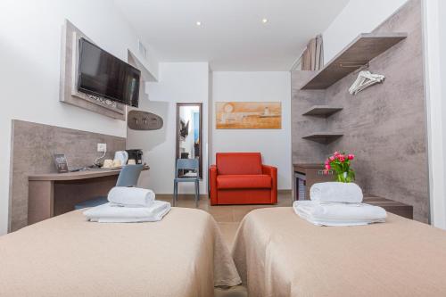 um quarto de hotel com duas camas e uma cadeira vermelha em Hotel Repubblica em Milão