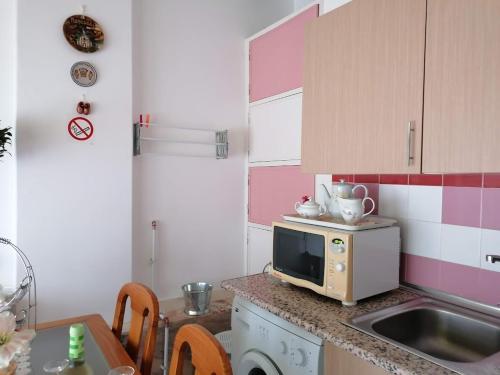 a kitchen with a sink and a microwave on a counter at Lisbon Coast Flat in Quinta de Santo António