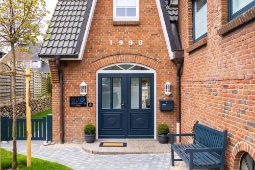 a blue door on a brick building with a bench at Sylt Seascape III in Tinnum