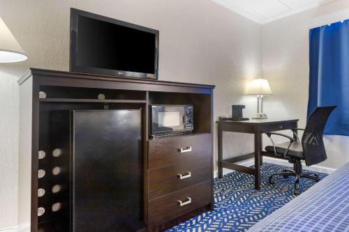 a hotel room with a television on a dresser with a desk at Econo Lodge Hicksville in Hicksville