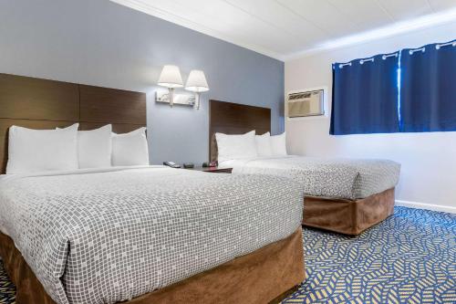 a hotel room with two beds and blue curtains at Econo Lodge in Hicksville