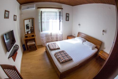 a small bedroom with a bed and a television at Apartments Kole in Rafailovici