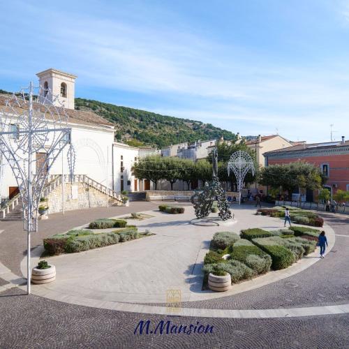 une cour avec des buissons et des arbres et un bâtiment dans l'établissement M.Mansion, à San Giovanni Rotondo
