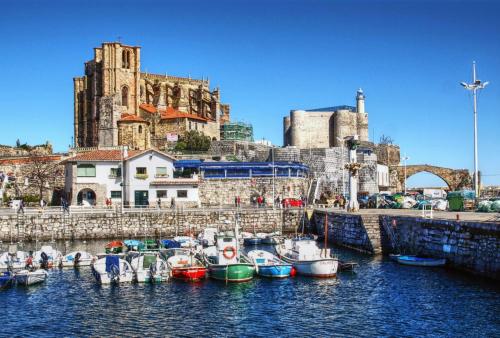 a group of boats docked in a harbor with a castle at Apt Las Olas Cotolino con parking a 2' de la playa in Castro-Urdiales