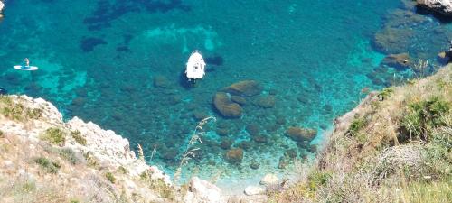 a boat in the water next to a cliff at B&B La mia Isola in Castelluzzo