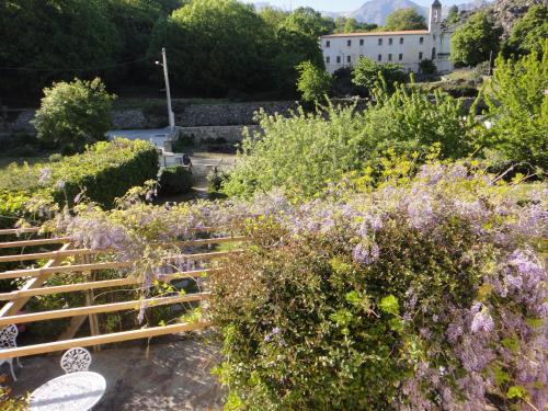 un giardino con fiori viola e un edificio bianco sullo sfondo di Casa Balduina a Calacuccia