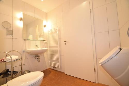 a white bathroom with a toilet and a sink at Haus Ankerplatz Apartment 2 2 in Büsum