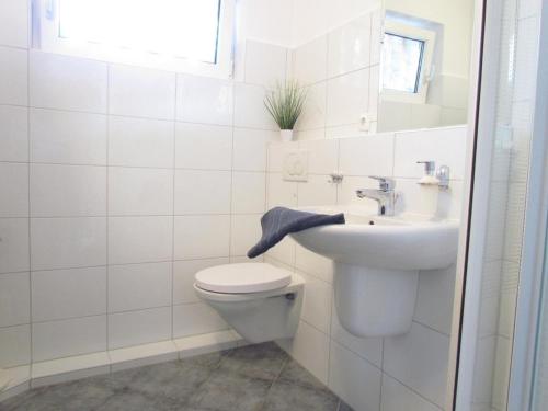 a white bathroom with a toilet and a sink at "LüttMeerDeern", Im Grünen Winkel 10 - Wohnung im Erdgeschoss in Kellenhusen