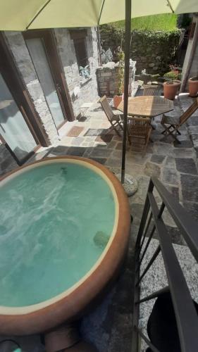 a hot tub with an umbrella on a patio at Locanda del Sasso Rooms in Crodo