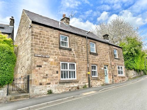 un viejo edificio de ladrillo al lado de una calle en The Old Butchers Cottage, en Matlock