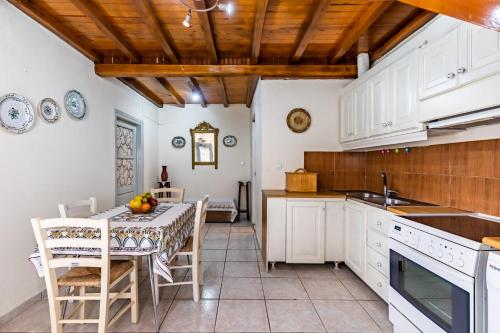 a kitchen with white cabinets and a table and chairs at VASIA HOUSE in Skopelos Town