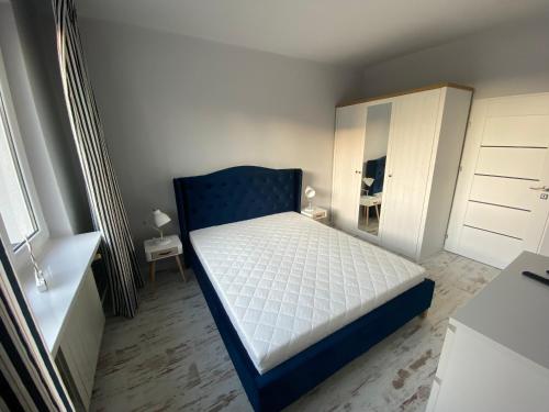 1 dormitorio con 1 cama con cabecero azul en Apartament nad jeziorem Białym, en Augustów