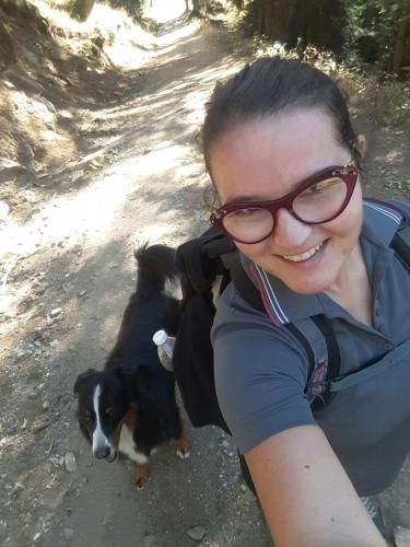 a woman with glasses is smiling next to two dogs at Locanda del Sasso Rooms in Crodo