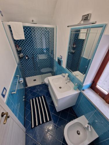 La salle de bains est pourvue de carrelage bleu, d'un lavabo et de toilettes. dans l'établissement Casa Vacanza "A Casa di Raffaele", à Ravello