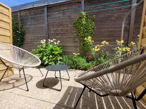 a patio with two chairs and a table and flowers at Hôtel de charme & SPA Le Grand Large in La Bernerie-en-Retz