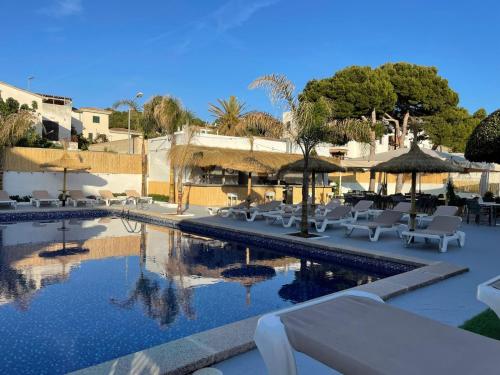 a pool with tables and chairs and umbrellas at Hotel Chevy & Suites in Cala Ratjada