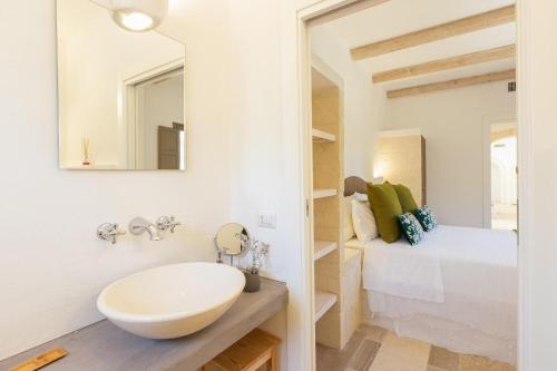 a bathroom with a sink and a bed and a mirror at Lamia del Bosco con Piscina in Ostuni