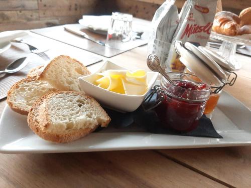 a plate of food with bread and butter and jam at Locanda del Sasso Rooms in Crodo