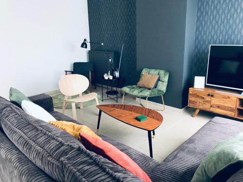 ein Wohnzimmer mit einem Sofa und einem TV in der Unterkunft Maison Remy in Ypern