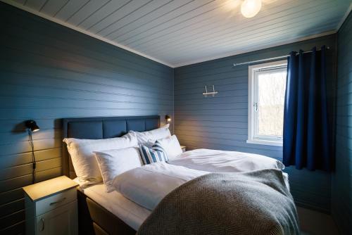 a blue bedroom with a bed and a window at Hustadvika Havhotell - by Classic Norway Hotels in Farstad