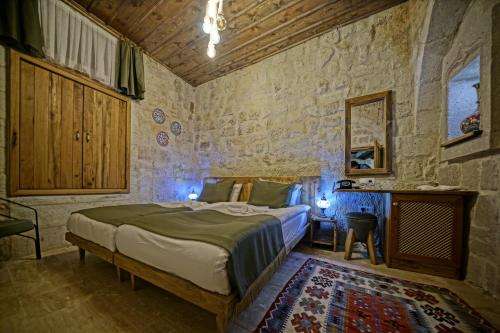 a bedroom with a bed and a stone wall at Vigneron Cave Hotel in Nevsehir