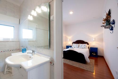 ein Badezimmer mit Waschbecken und ein Bett in einem Zimmer in der Unterkunft Delmira Vineyard House in Águas de Moura