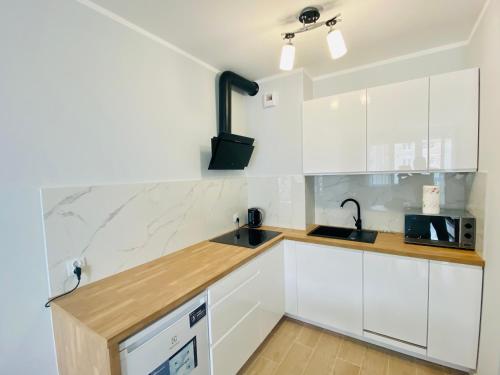 een witte keuken met een wastafel en een magnetron bij Apartment Insat IV in Szczecin