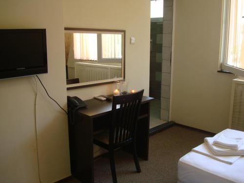 a room with a desk with a mirror and a television at Guest House Lazur in Burgas