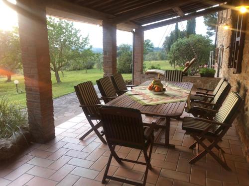 uma mesa de madeira e cadeiras num pátio em Podere Belvedere Villa Classic Tuscan em Magliano in Toscana