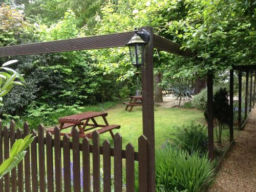 a wooden fence with a picnic table in a garden at Andel Lodge in Kings Lynn