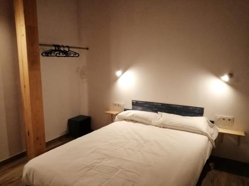 sypialnia z białym łóżkiem i 2 lampkami na ścianie w obiekcie Casa rural Lastoetxe w mieście Larrauri
