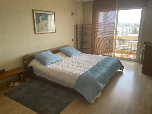 una camera da letto con un grande letto con cuscini blu di Residence Elite appartement de luxe a Casablanca