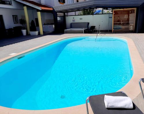 a blue swimming pool with two chairs next to it at Milfontes Guest House - Duna Parque Resorts & Hotels in Vila Nova de Milfontes