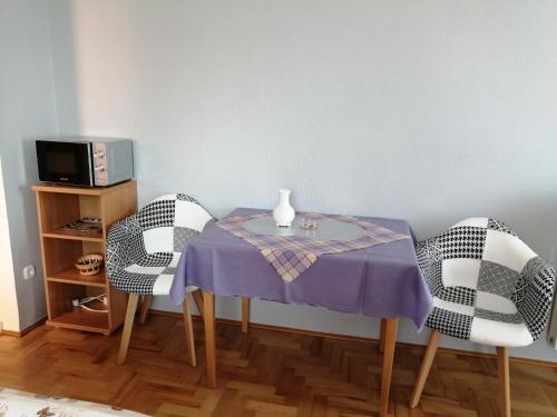 - une table à manger avec 2 chaises et un vase dans l'établissement Anita Apartmanház, à Balatonfüred